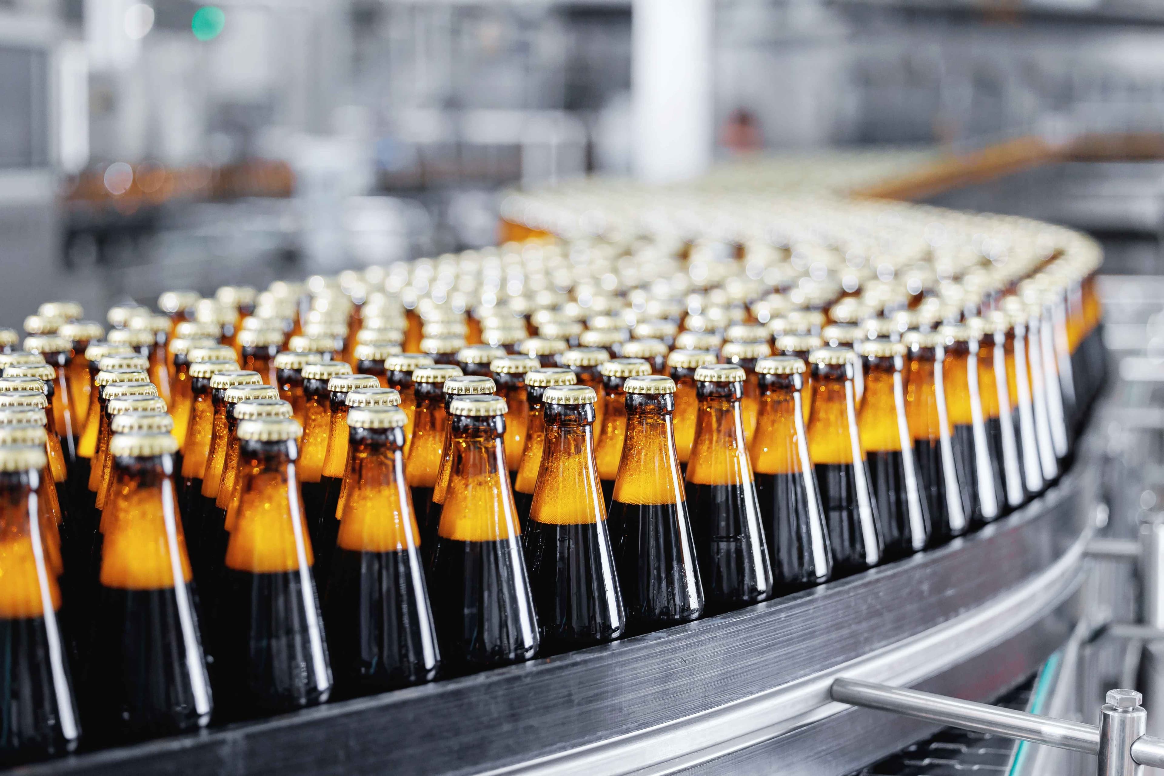 Brown glass beer bottles on conveyor belt Automated brewery industry manufacturing with sunlight.